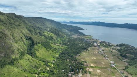 Carretera-Pulau-Samosir-Junto-Al-Lago-Toba-Con-Exuberante-Paisaje-Y-Agua,-Vista-Aérea