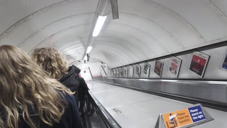 Las-Personas-Están-Bajando-Las-Escaleras-Mecánicas-En-La-Estación-De-Oxford-Street-En-Londres,-Inglaterra,-Lo-Que-Ilustra-El-Concepto-De-Movilidad-Urbana-Y-Transporte-Eficiente-En-áreas-Metropolitanas-Bulliciosas.