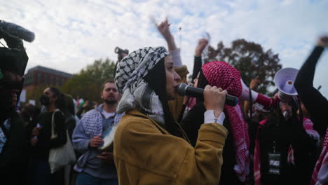 Un-Primer-Plano-De-Una-Mujer-árabe-Con-Una-Keffiyeh-Gritando-Ante-Un-Micrófono-En-Una-Protesta-A-Favor-De-Palestina