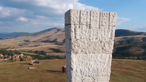 Monument-to-the-Executed-Partisans-of-Zlatibor-Serbia,-drone-dolly-in-shot-revealing-beautiful-mountains-in-the-background-with-the-fluffy-clouds-above