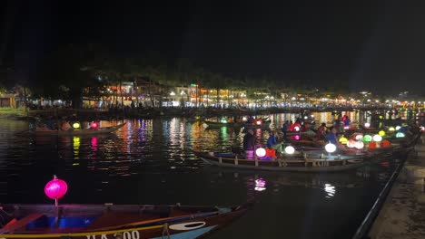Laternenboote-Aus-Hoi-An-In-Vietnam-Liegen-Am-Fluss-Thu-Bon-Festgemacht,-Dahinter-Der-Nachtmarkt-Von-An-Hoi