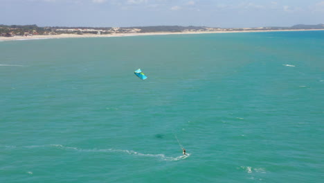 Aerial-view-of-person-practing-kite-surf-and-small-village-around,-Cumbuco,-Ceara,-Brazil