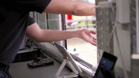 Worker-hands-prepared-packaged-food-order-through-food-trailer-truck-window-to-customer-holding-wallet,-slow-motion-4K