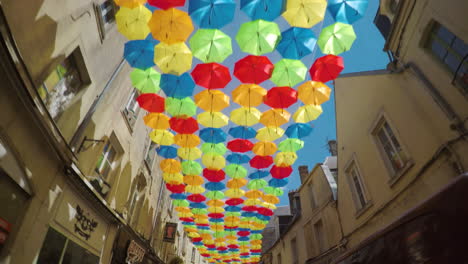 Driving-underneath-multi-colored-umbrellas-hanging-in-street-of-small-town