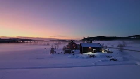 Twilight-descends-on-Bysjon-Lake,-Sidensjo,-Sweden,-with-cozy-cabins-and-a-serene-snowscape