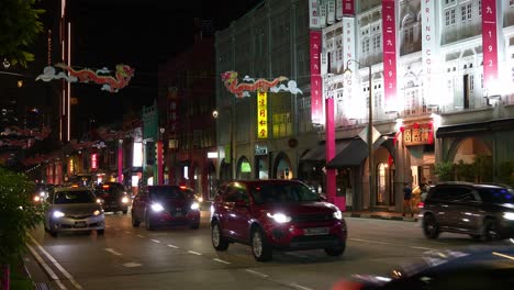 Night-vehicle-traffic-on-Upper-cross-street-in-Chinatown,-street-decorated-with-dragon-themed-props-for-Chinese-lunar-new-year,-static-shot