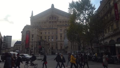 People-walk-across-street-in-front-of-Opera-House-Palais-Garnier-in-Paris