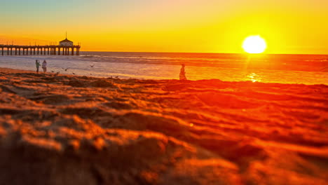 Puesta-De-Sol-Sobre-La-Playa-De-Manhattan-En-Los-ángeles-Con-Muelle-Desde-Un-Lapso-De-Tiempo-De-ángulo-Bajo