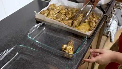 A-person-lifts-chicken-pieces-and-places-them-into-a-glass-bowl,-symbolizing-the-process-of-cooking-and-food-preparation