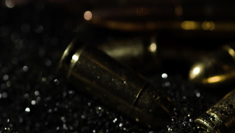 Close-up-of-9mm-and-300-BLK-OUT-bullets-cascading-down-in-slow-motion,-with-a-dark,-moody-backdrop