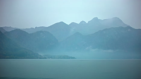 Vapor-clouds-forming-and-disappering-in-mountains-over-lake,-timelapse