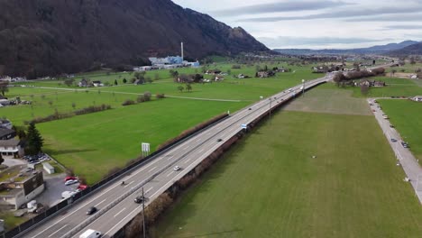 Traffic-on-swiss-highway-between-green-fields-and-alp-mountains