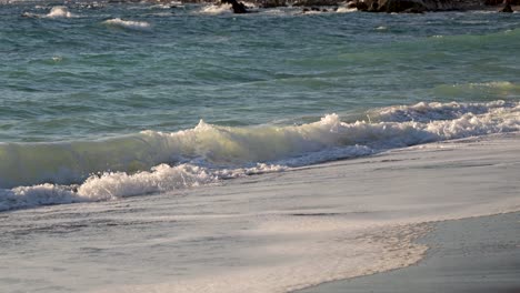 Slow-motion-ocean-waves-crashing-on-sandy-beach-during-daytime