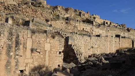 Antiguas-Ruinas-Romanas-Iluminadas-Por-El-Sol-En-Dougga,-Muros-Y-Arcos-De-Piedra,-Cielo-Despejado,-Sitio-Histórico