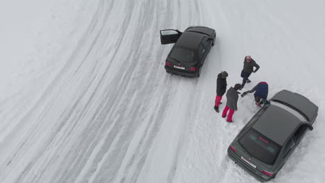 People-digging-out-car-stuck-in-white-snow-at-ice-circuit-in-Norway