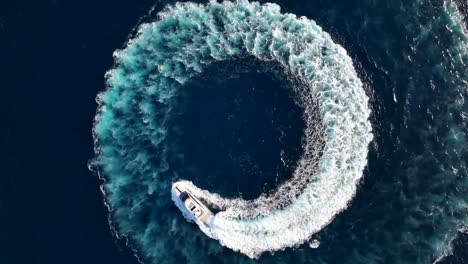 Top-down-drone-shot-of-luxury-yacht-driving-a-circle-at-sea-while-zooming-in