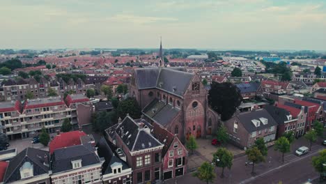 Eine-Historische-Kirche-In-Einer-Europäischen-Stadt-In-Der-Abenddämmerung,-Die-Eine-Heitere-Stimmung-über-Die-Stadtlandschaft-Verbreitet,-Luftaufnahme