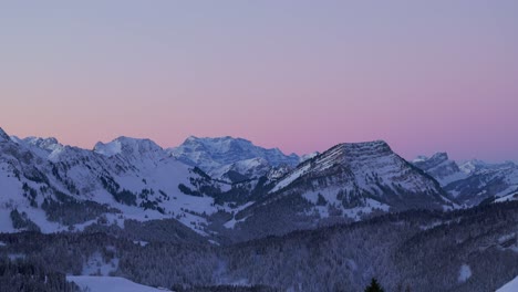 Mit-Einer-Drohne-Aufgenommene-Aufnahmen-Zeigen-Den-ätherischen-Charme-Des-Sonnenaufgangs,-Der-Die-Silhouette-Einer-Schneebedeckten-Bergkette-Erhellt
