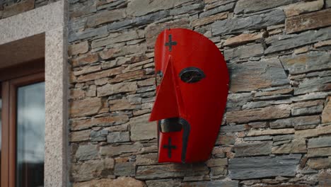 Vivid-Red-Careto-Mask-on-Stone-Wall,-Podence-Portugal