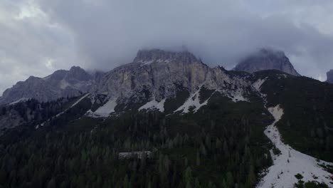 Stratus-clouds-on-rocky-mountain-peaks-aerial-rising,-Dolomites-Italy