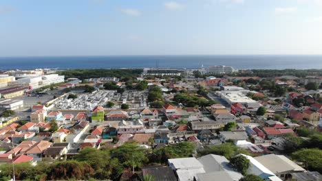 Panoramic-aerial-pan-across-vibrant-orange-roofs-in-Willemstad-Curacao,-view-to-sea