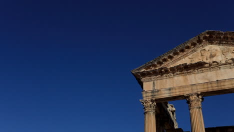 Antiguas-Ruinas-Romanas-Iluminadas-Por-El-Sol-En-Dougga-Contra-Un-Cielo-Azul-Claro,-Destacando-La-Arquitectura-Histórica.