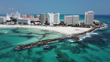 Cancun-beach-with-clear-turquoise-waters-and-bustling-hotel-zone,-aerial-view