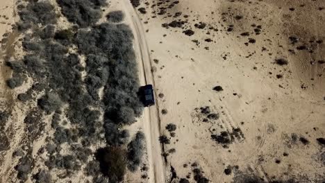 Vehicle-driving-through-desert,-captivating-experience-vast-barren-terrain