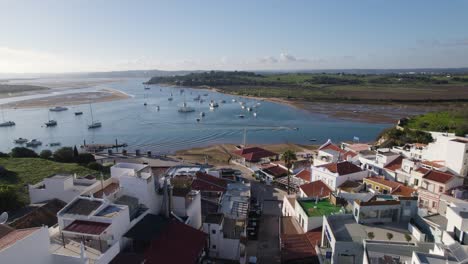 Anchored-sailboats-in-the-bay-in-fishing-village-Alvor,-Portugal,-aerial