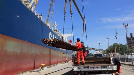 Arbeiter-Laden-Fracht-Auf-Ein-Schiff-Im-Sonnigen-Hafen-In-Argentinien,-Reflektierende-Sicherheitsausrüstung,-Tagsüber