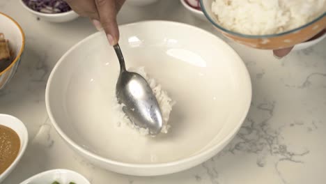 Closeup-of-dipping-white-jasmine-rice-to-a-white-bowl-delicious-vibrant-vegan-dish
