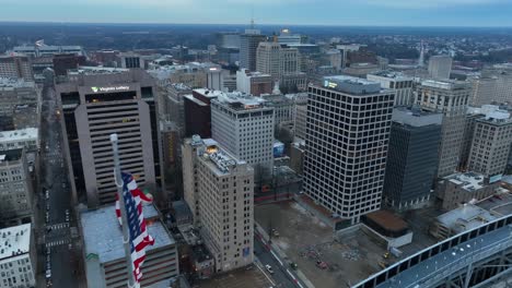 Waving-American-flag-on-top-of-skyscraper-with-downtown-view-in-Richmond,-Virginia