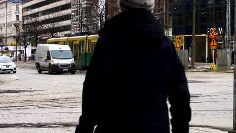 Tranvía-Verde-Número-3-Y-Coche-Negro-En-La-Intersección-De-La-Ciudad-De-Helsinki,-Durante-El-Día,-Escena-De-Tráfico-Urbano,-Cielo-Nublado