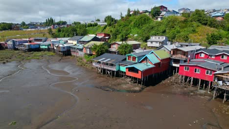 Dolly-in-flyover-of-the-Castro-stilt-houses-in-Chiloé,-low-tide,-low-water-level-sunny-day,-Chile