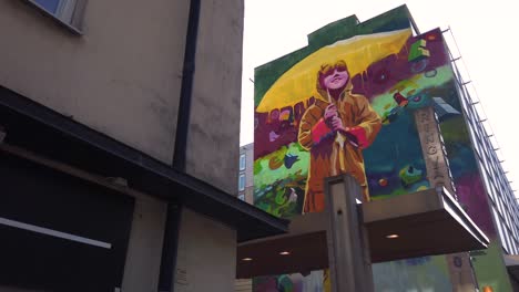 Large-mural-painting-of-young-girl-with-umbrella-in-Stockholm,-Sweden