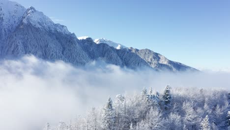 Montañas-Nevadas-De-Bucegi-Que-Se-Elevan-Por-Encima-De-Las-Nubes-Con-Un-Cielo-Sereno,-Paisaje-Invernal