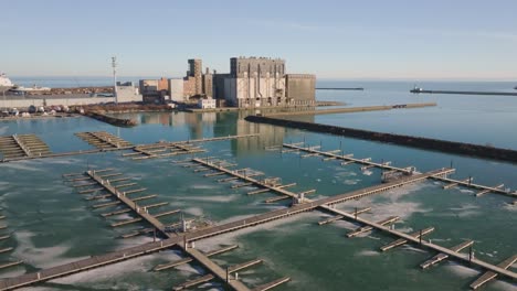 Port-colborne-marina-with-empty-docks-and-industrial-buildings,-calm-day,-aerial-view