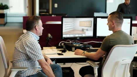 Two-casual-man-office-workers-enjoying-some-small-talk-during-work-while-sitting