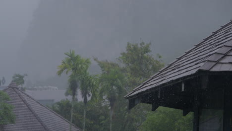 Rainfall-on-rooftops-in-southern-Krabi,-Thailand,-during-the-tropical-rainy-season,-surrounded-by-lush-green-trees