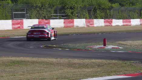 Race-car-going-over-curbstones-through-chicane-at-high-speed,-tracking-shot