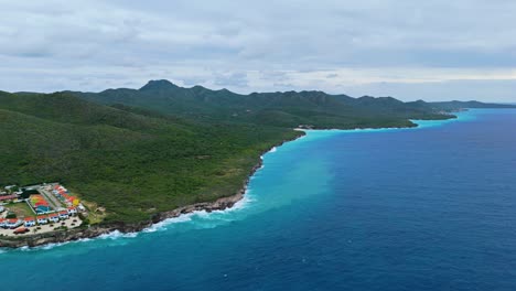 Lush-sloping-green-mountains-to-coastline-of-Westpunt-Curacao-Caribbean-Island,-panoramic-aerial