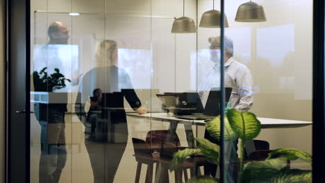 Colleagues-in-meeting-room-standing-instead-of-sitting,-healthy-work-environment