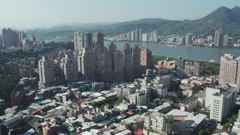 Vista-Aérea-De-Zhuwei,-Horizonte-De-La-Ciudad-De-Taipei-Con-Río-Y-Montañas-Al-Fondo