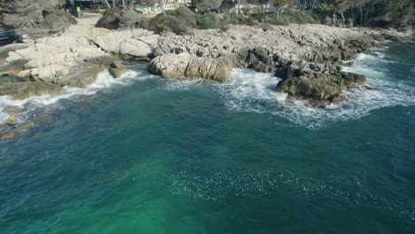 Mallorca-with-this-mesmerizing-footage-of-the-raw-power-of-big-surfer-waves-crashing-against-majestic-cliffs,-rocky-formations,-and-ancient-stones