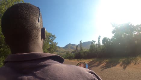 Point-of-view-shot-of-an-African-man-driving-a-motor-bike-taxi-through-a-remote-rural-African-mountain-landscape