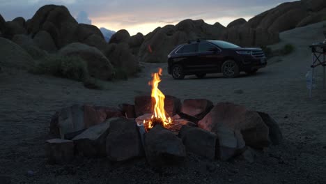 Campfire-Between-Rocks-and-Car,-Camping-in-Wilderness