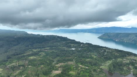 Samosir-island-in-Sumatra-with-lush-greenery-and-lake-Toba-under-cloudy-skies,-aerial-view