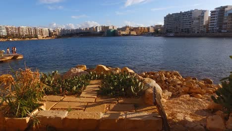 Stone-Shoreline-And-The-High-Rise-Hotel-Development-At-Paceville-St-Julians,-Malta