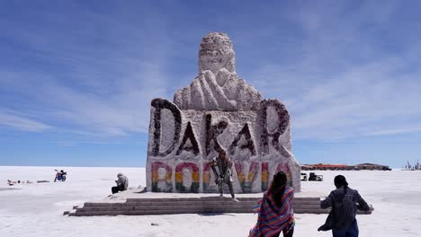 Tourists-pose-for-photos-at-Dakar-Monument-on-Uyuni-Salt-Flat,-Bolivia