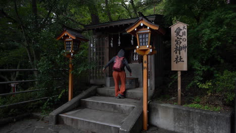A-woman-kneels-and-bows-in-prayer,-mirroring-the-local-customs,-at-a-small-wooden-joss-house-or-shrine-tucked-away-in-Fujikawaguchiko,-Japan